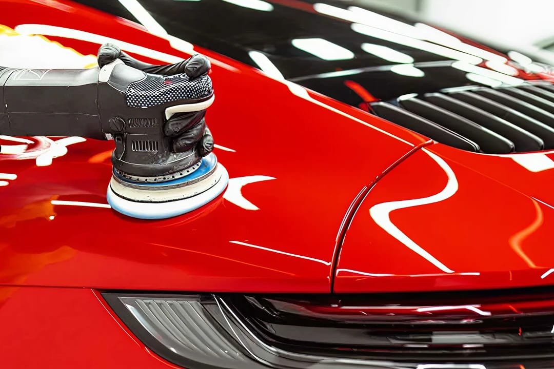 Machine polishing a red sports car to a mirror finish