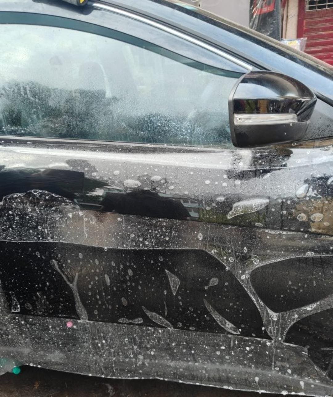 Protection film being wet-applied across a black car door