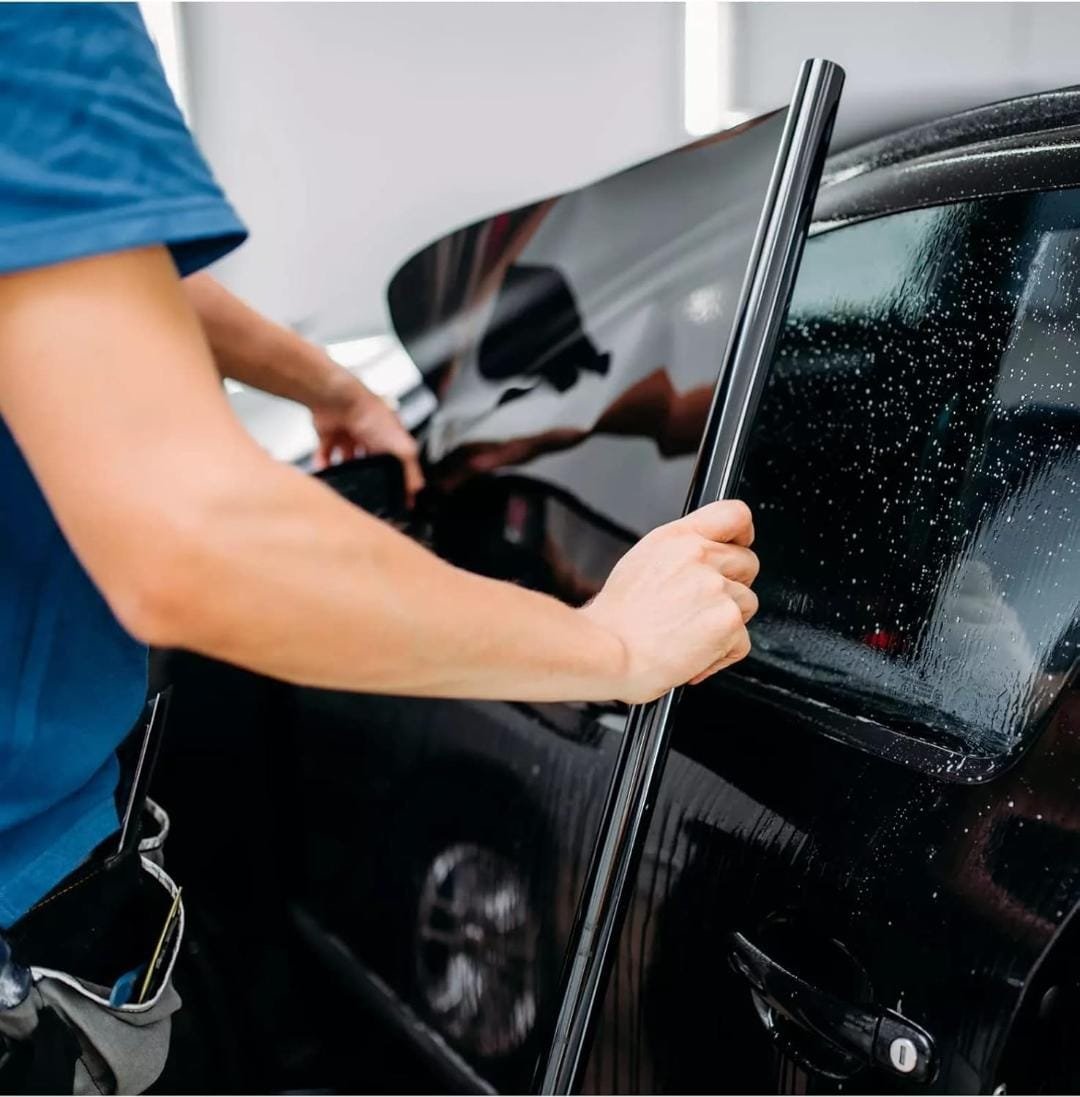 Technician applying tint film to a car window