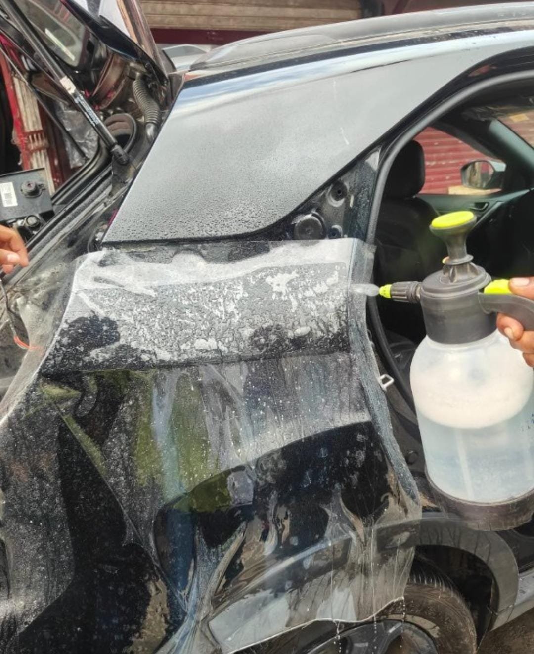 Chrome wrap film being wet-applied to a car pillar and panel