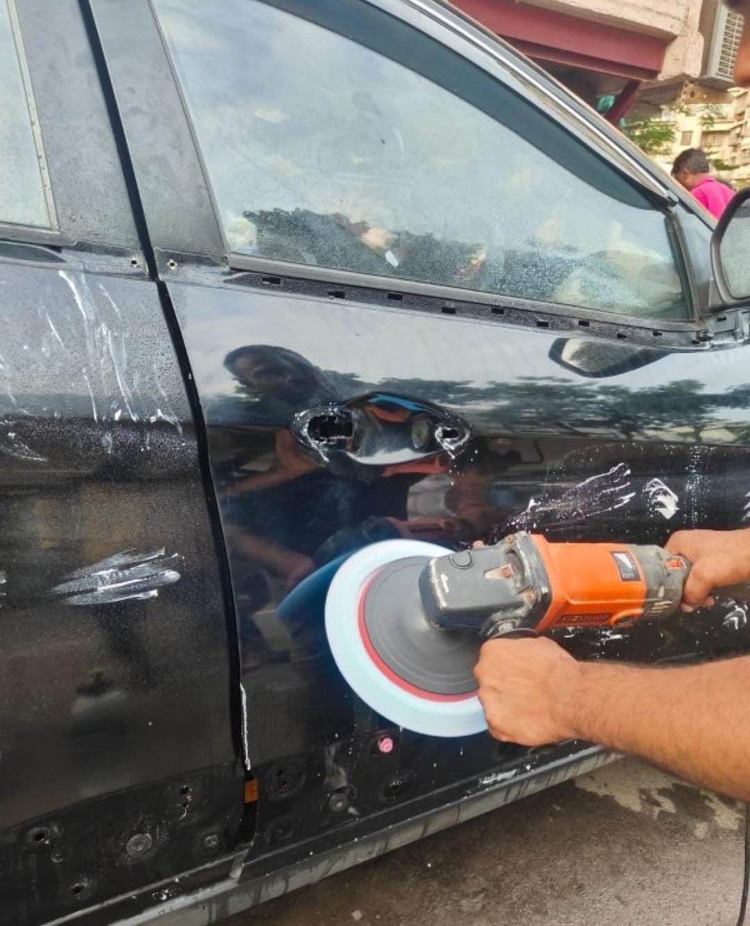 Panel being refinished and buffed on a black car door