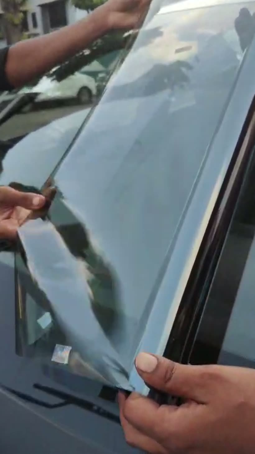 Pre-cut sun control film being positioned on a car windshield